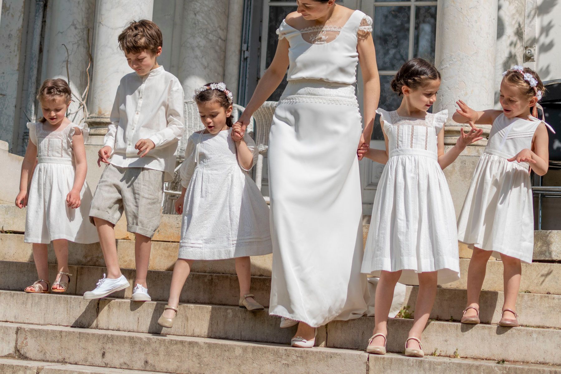 cortège de petites filles et petits garçons habillés grâce aux deux cours de couture cortège enfant d'Artesane descendant les marches avec la mariée.